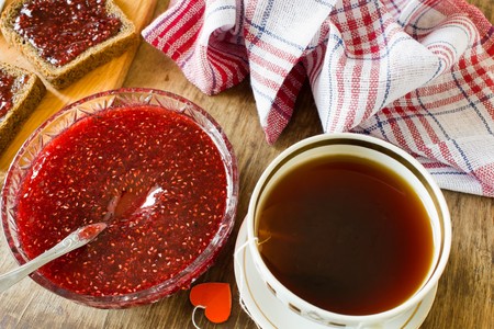 A light breakfast or lunch a lot of raspberry jam in a plate and a slice of black bread with jam on topの写真素材