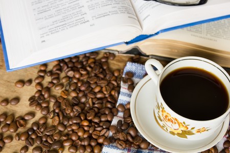 Book glasses  black coffee cup  and blue checkered napkinの写真素材