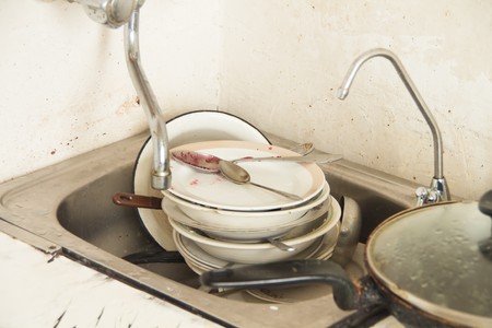A lot of dirty dishes in the old poorly furnished kitchenの写真素材