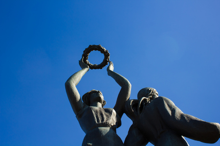 The statue is holding a wreath in the hands against the blue skyの写真素材