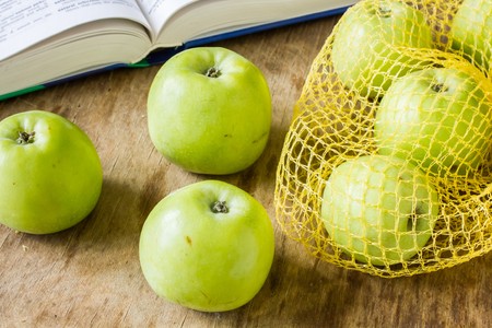 Green apples are medium in size on white lace napkin on a wooden table vintageの写真素材