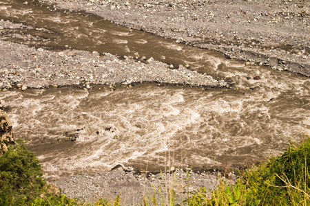 Dirty fast flowing mountain stream in early summer