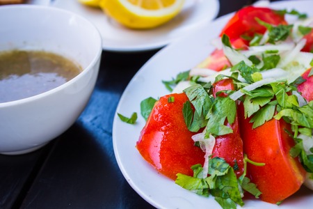 Delicious fresh salad with tomato sauce sliced bread and cut lemon on a stylish black tableの写真素材