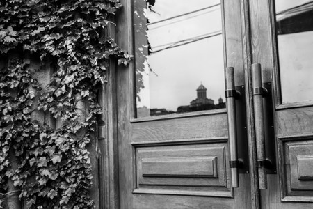 Black and white photo beautiful stylish wooden door next to ivy and a reflection of the Cathedral of Tbilisi, Georgiaの写真素材