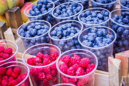 Fresh ripe raspberries and blueberries on the market counterの写真素材