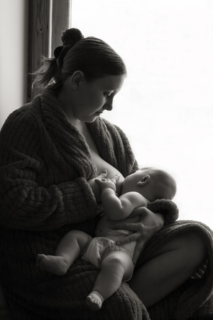 Woman breastfeeding near a window, black and white