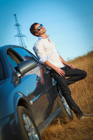 Stylish man in sunglasses standing near his carの写真素材