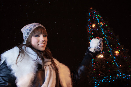 Beautiful 16 year old girl plays snowballs near a big Christmas treeの写真素材