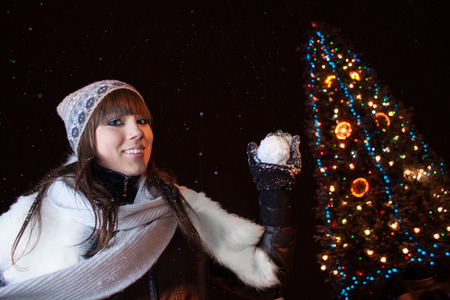 Beautiful 16 year old girl plays snowballs near a big Christmas treeの写真素材