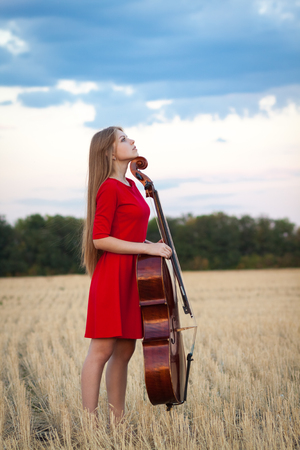 Woman musician violoncellist with cello in fieldの写真素材