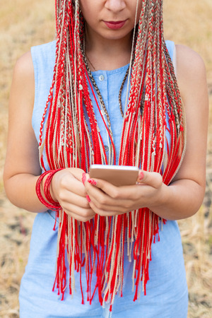 Caucasian woman with african pigtails using smartphone outdoorsの写真素材