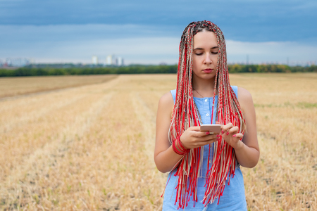 Caucasian woman with african pigtails using smartphone outdoorsの写真素材
