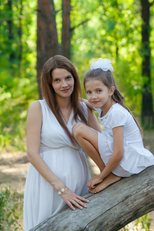 Little girl and her pregnant mother in the forestの写真素材