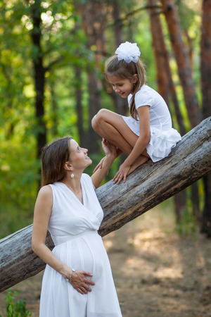 Pregnant woman and her daughter in the forestの写真素材