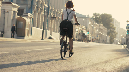 Young woman with red hair riding a bike in park bottom view. Woman bike parkの写真素材