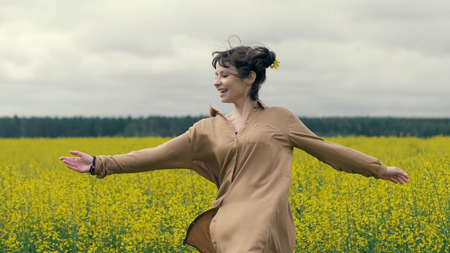 Happy woman enjoys a summer walk in field. Summer field yellow flowersの写真素材