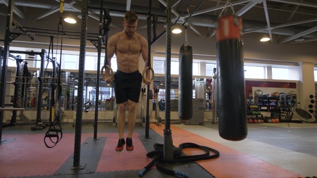 Sport man training workout exercise on gymnastic rings in fitness club