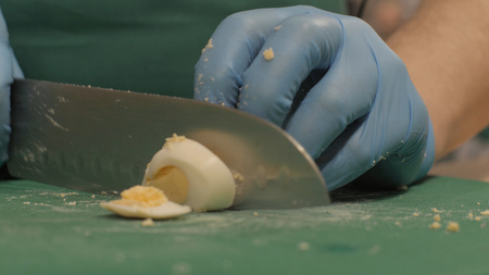 Chef cook cutting egg on slices on board in restaurant kitchen close up