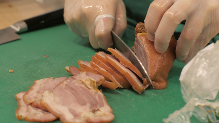 Cook using knife for cutting smoked pork brisket while cooking in close up