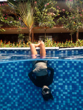 A pregnant woman in upside down position in swimming pool at a resort.の写真素材