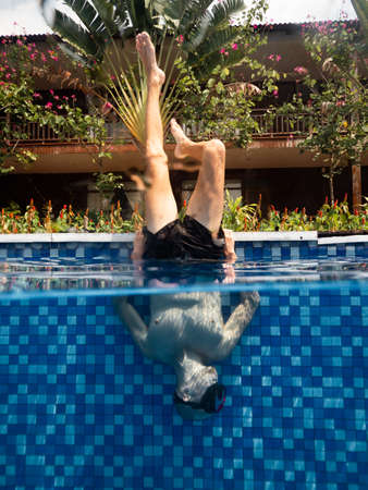 Unique Photoshoot in a holiday resort, a man doing updside down postion in pool.の写真素材