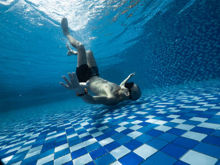 A young Caucasian man in snorkel mask and short underneath the swimming poolの写真素材