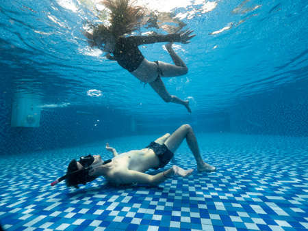 Pregnant couple in the swimming pool in a unique maternity photoshoot.の写真素材