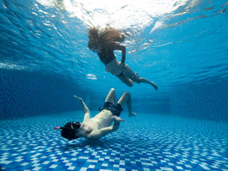 Underwater maternity photoshoot of a young pregnant couple in the swimming poolの写真素材