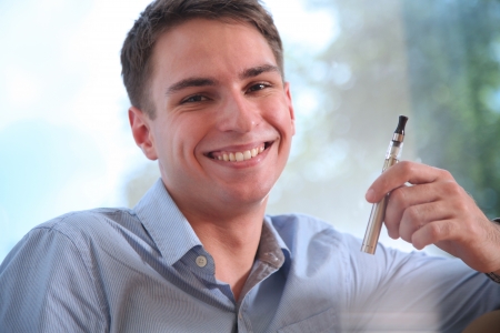 Young happy smiling man smoking electronic cigarette  e-cigarette の写真素材