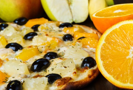 Delicious pizza with black olives and pineapples and orangesの写真素材