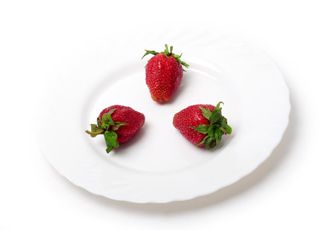 An appetizing strawberry on a white plate at the white backgroundの写真素材