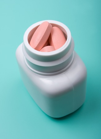 The white bottle with pills on a green backgroundの写真素材