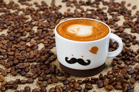 Coffee cup and beans scattered on sacking backgroundの写真素材