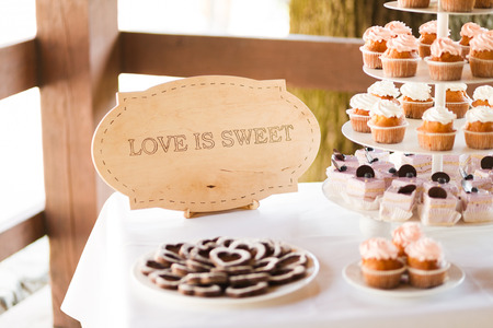 Served festive candy bar table with cupcakes tower and "love is sweet" signの写真素材