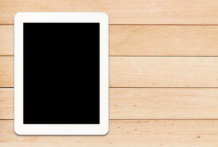 White tablet PC with black screen on a light wooden tableの写真素材