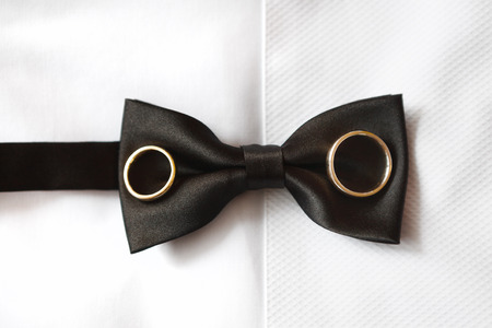 Wedding rings on a grooms black bow tieの写真素材