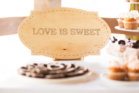 Served festive candy bar table with "love is sweet" signの写真素材