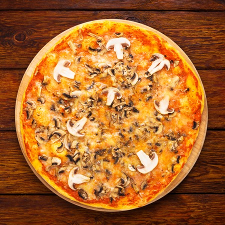 Delicious pizza with mushrooms - thin pastry crust isolated at wooden background, above viewの写真素材