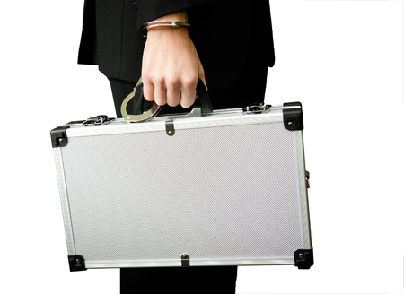 Bank finance security concept - businessman or guard hand  in handcuffs closeup holding suitcase with money isolated at white backgroundの写真素材