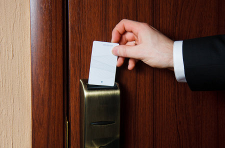 Man's hand in black suit inserts card to open electronic lock in hotel doorの写真素材