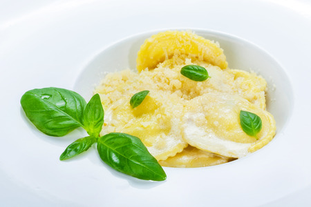 Traditional italian cuisine: ravioli with cream sause and parmesan decorated with basil.の写真素材