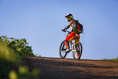 Extreme summer sports - young sportive strong woman or sportswoman riding downhill on mountain...