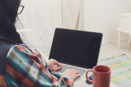 Young girl in protective computer glasses on white sofa with laptop.の写真素材