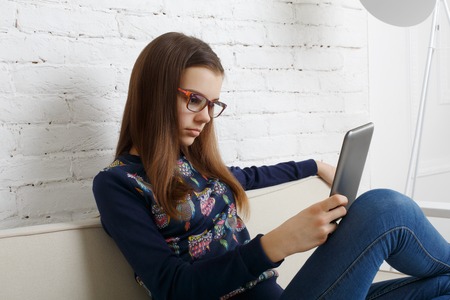 Teenager girl relax home, sitting on sofa with tablet computer.の写真素材