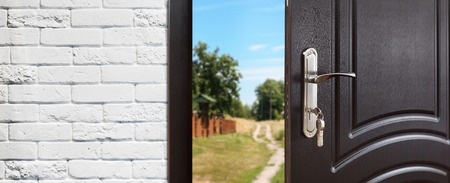 Entrance door half opened to nature background.