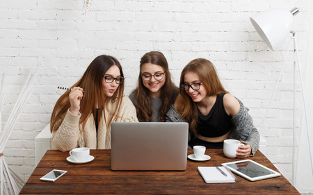 Portrait of three laughing girlfriends with laptop.の写真素材