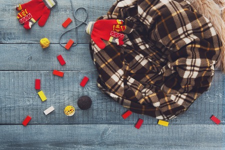 Cosy place for kittens to play and sleep - top view, flat lay. Serenity blue wood, chekered plaid blanket, wooden constructor details and red woolen mittens.の写真素材