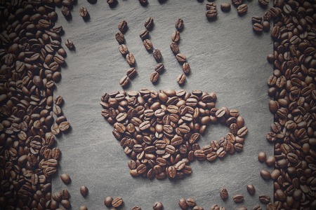 Cup from coffee beans with smoke. Heap of roasted coffee bean on grey stone surface texture. Coffee shop or cafe background. Natural stone and cup from beans. Soft color toning, top viewの写真素材
