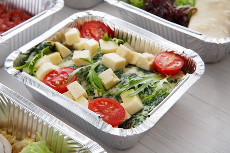 Healthy eating, diet concept. Take away organic food. Weight loss nutrition in foil boxes. Vegetables and omelette with cherry tomatoes, spinach and cheese at white woodの写真素材