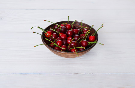 Sweet fresh cherries in a bowl on white rustic wood closeup, fruit snack backround. Healthy food at tableの写真素材